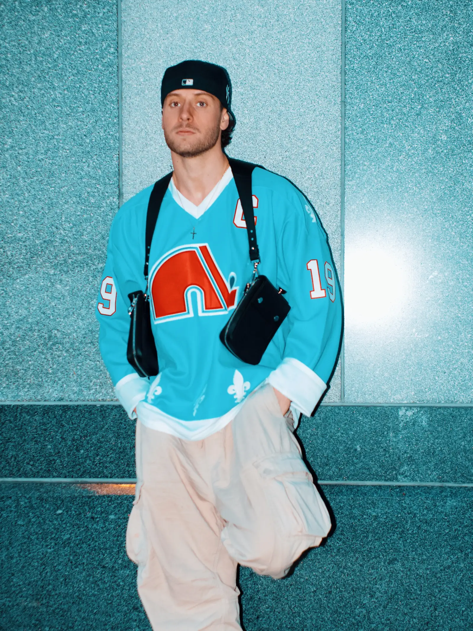 The Harness Bag worn across the chest, styled with a vintage hockey jersey